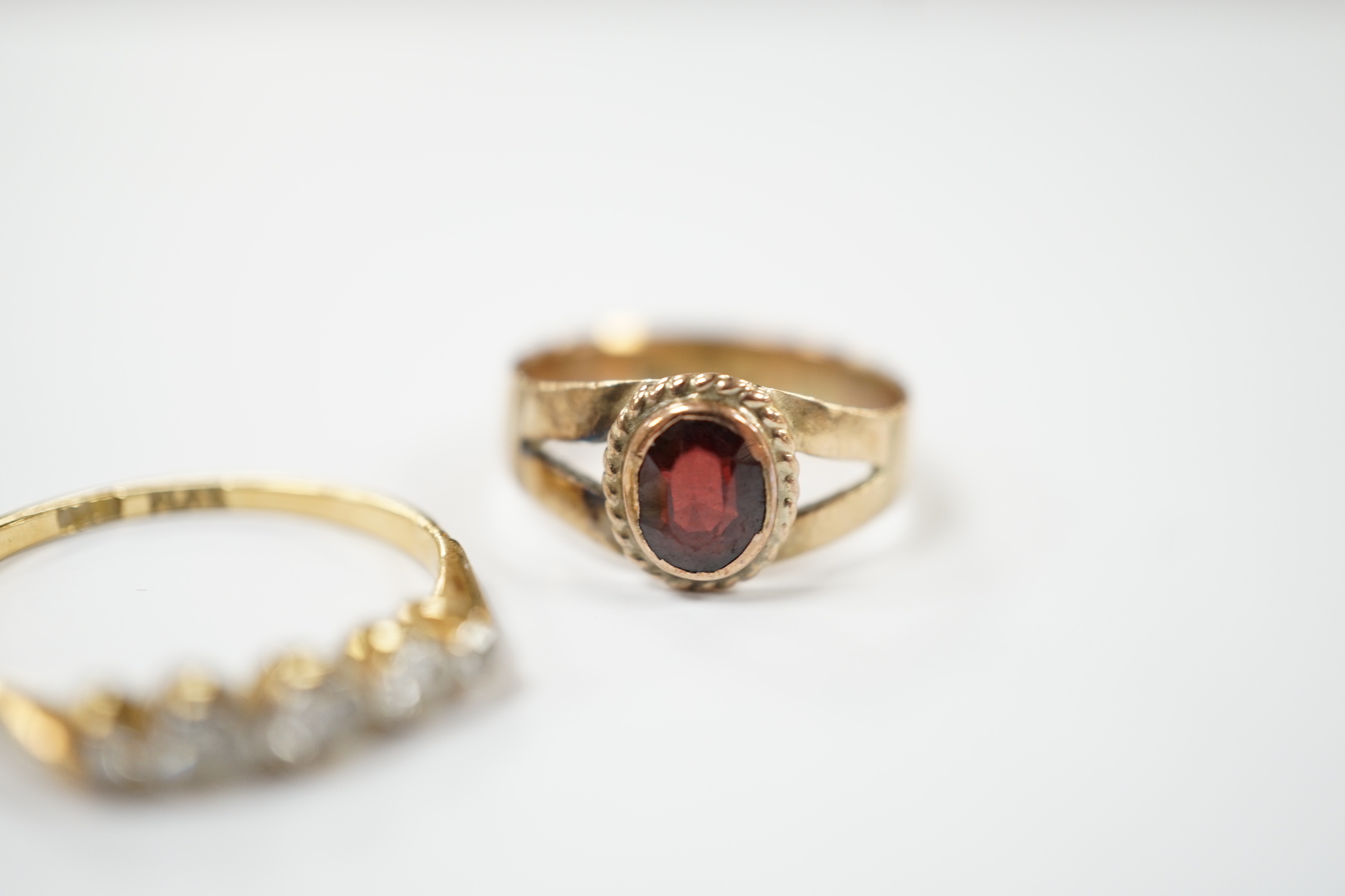 An 18ct, plat and graduated five stone diamond set half hoop ring, size M and a 14k and single stone garnet ring, size H.